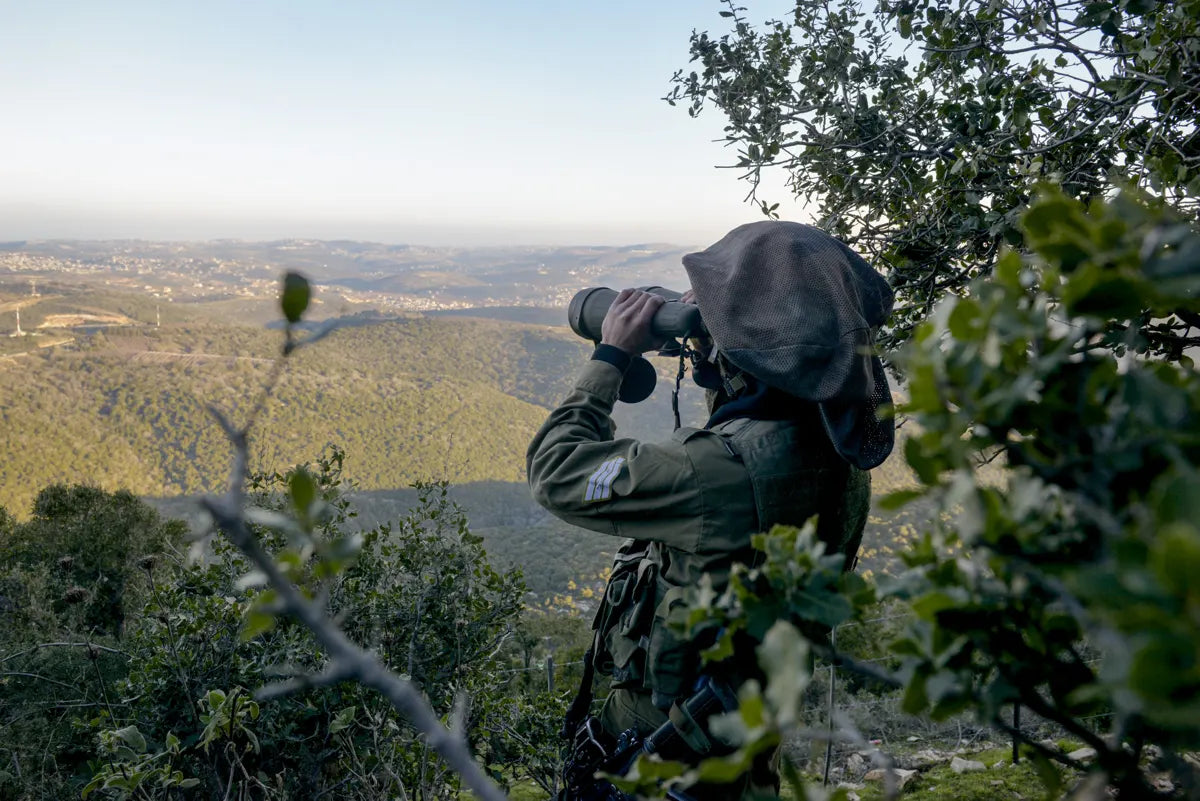 Soldier scanning a valley with binoculars